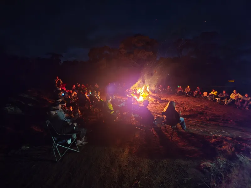 Club members and families sitting around a bright campfire at night