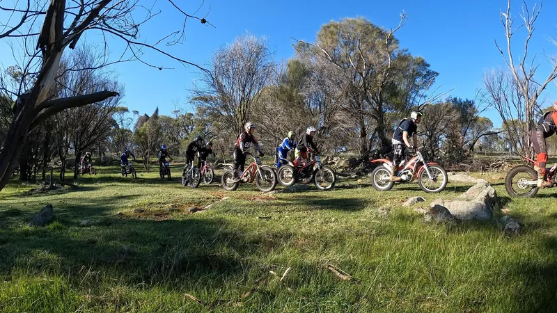 A line of Pathfinders trials riders moving through natural bush terrain