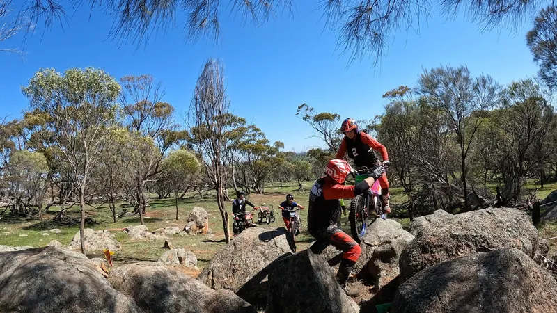 A rider tackling a rock section with another club member nearby for support