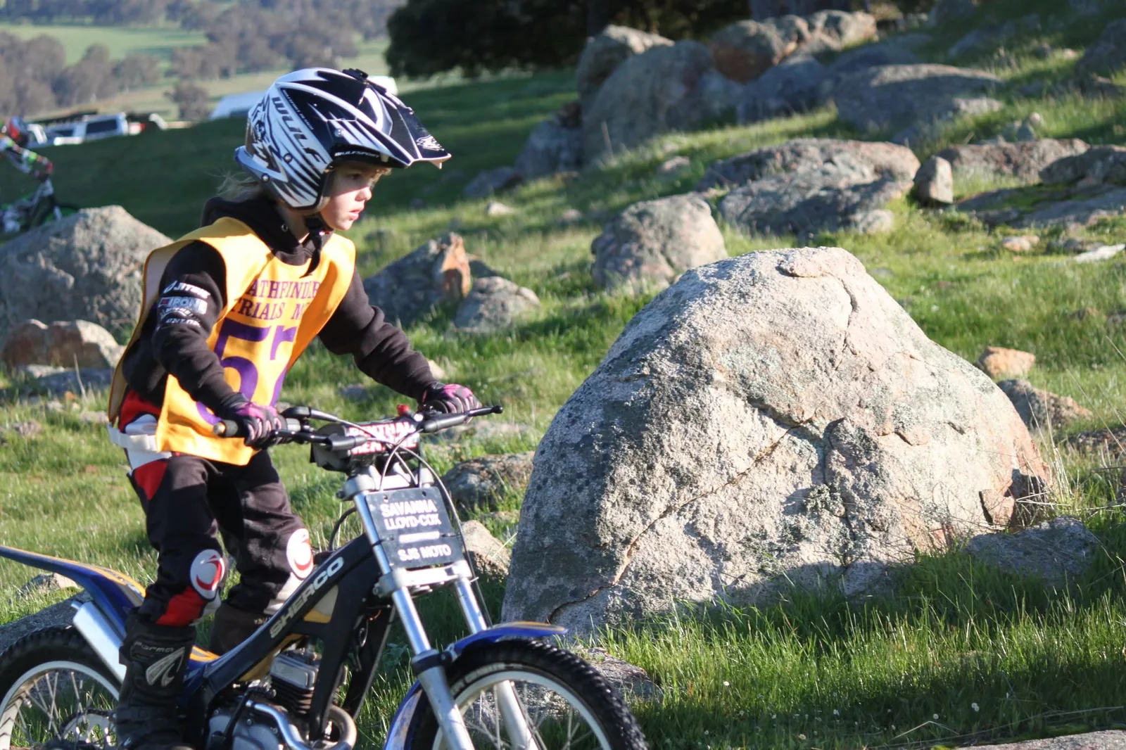 Small junior Pathfinders rider on a trials bike beside granite rocks