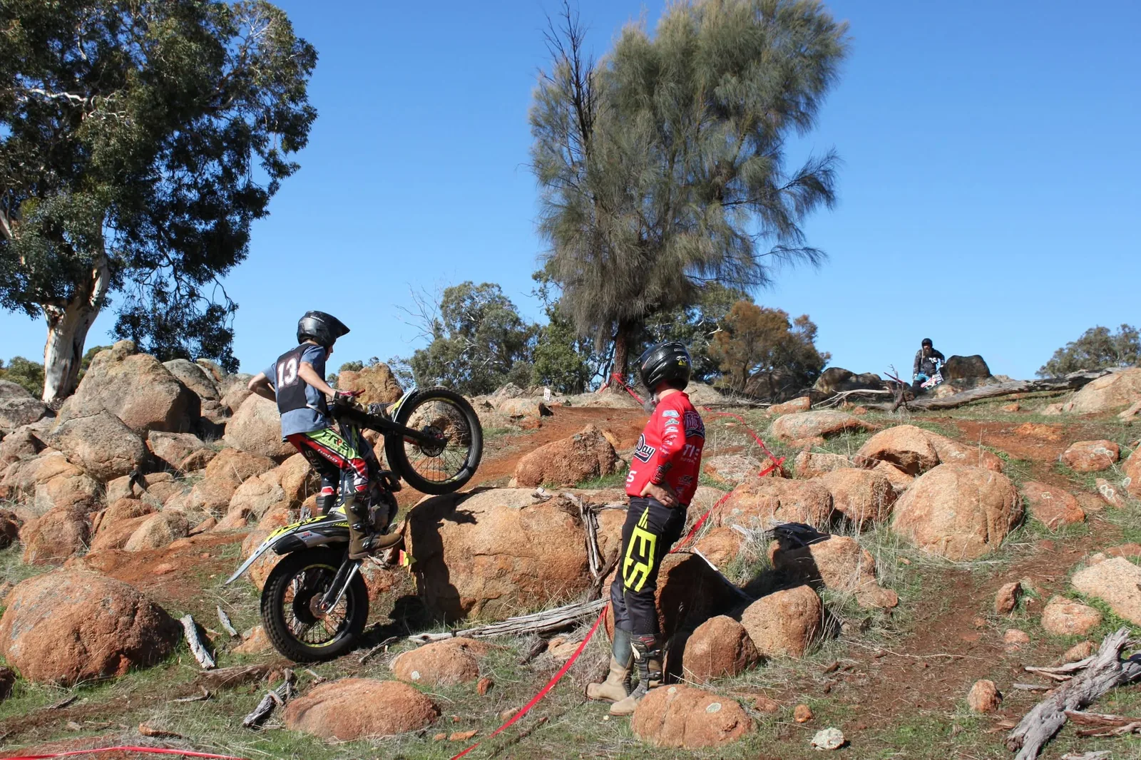Junior trials rider working through a rocky section with an adult nearby